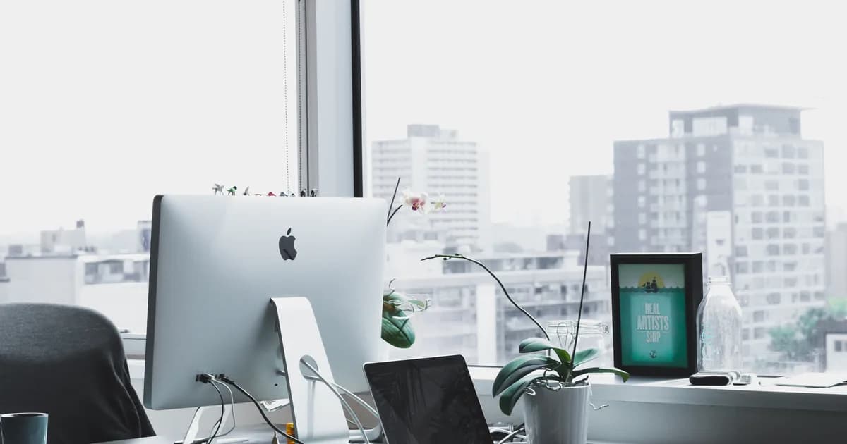 Minimal office workspace with laptop and monitor for focused resume writing.